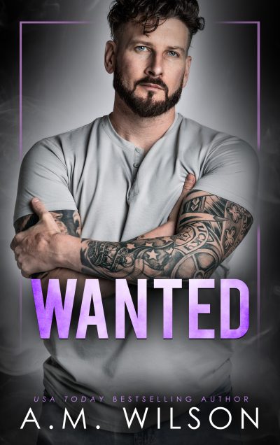Ebook cover for Wanted. Male model with tattoos wearing a gray tee shirt with his arms crossed over his chest. He has dark hair and dark facial hair